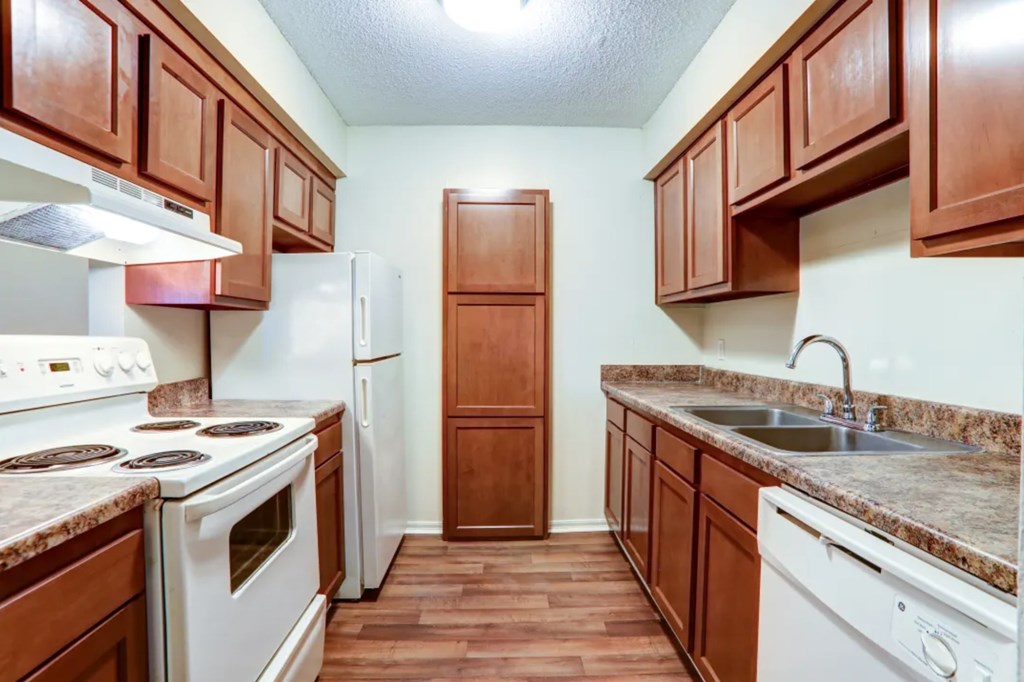 A kitchen with white appliances and brown cabinets.